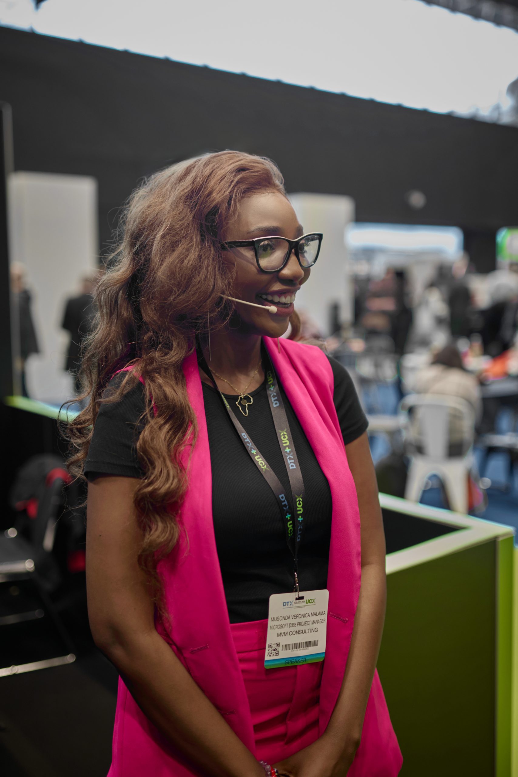 Business speaker in a pink suit at a trade show, corporate event photography by Captured By Luke Media