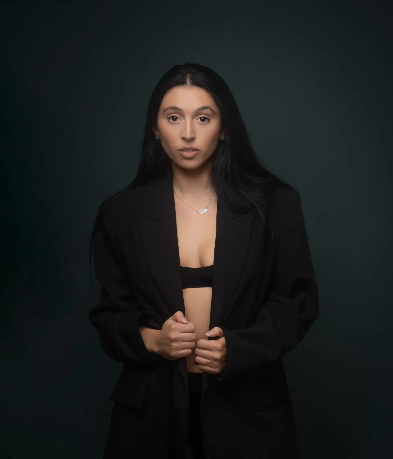 Dancer in a black blazer photographed against a dark teal studio background