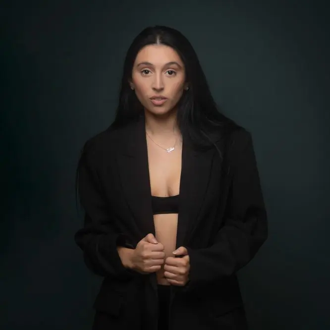 Dancer in a black blazer photographed against a dark teal studio background