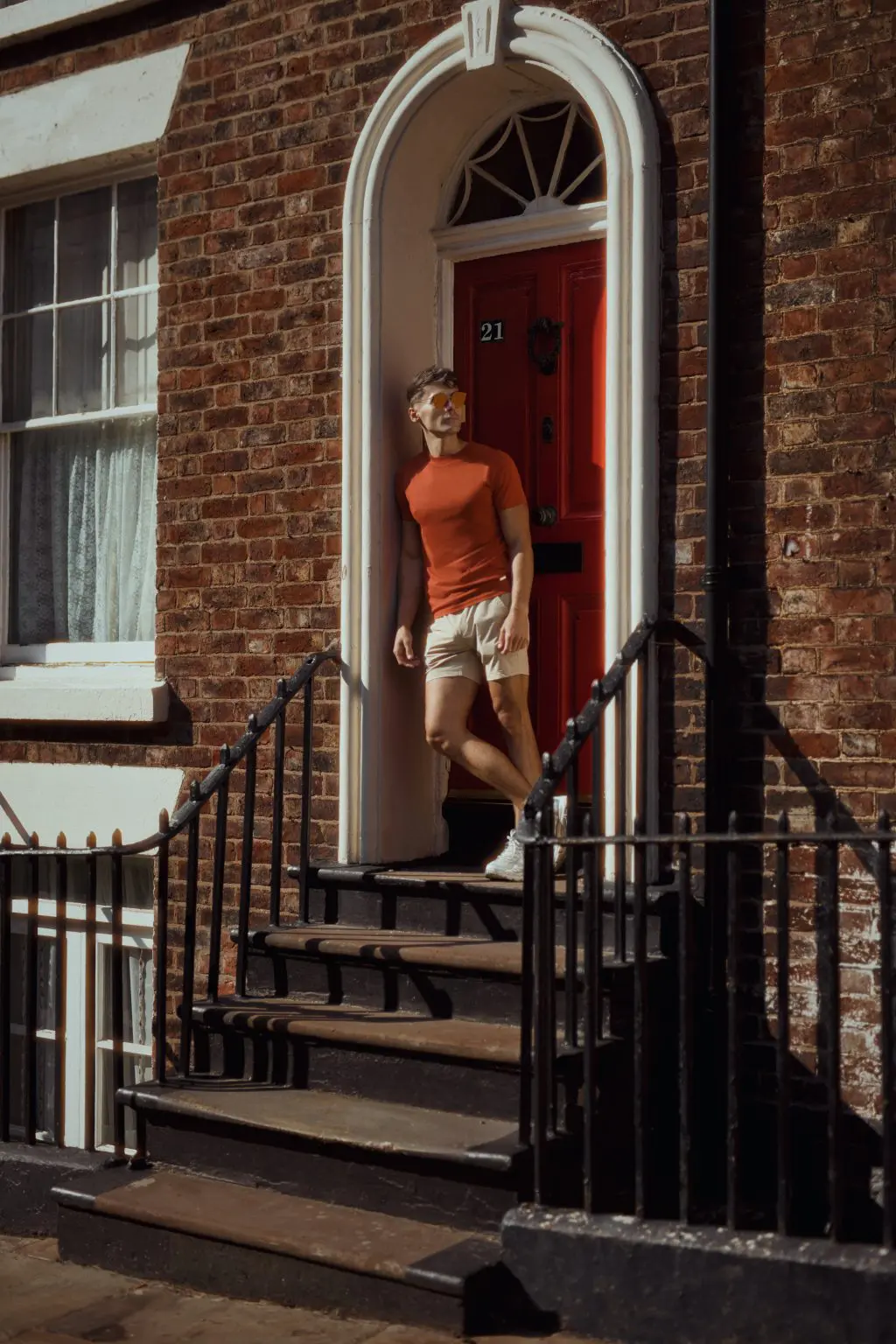 Influencer in an orange top standing in a Georgian doorway with black railings