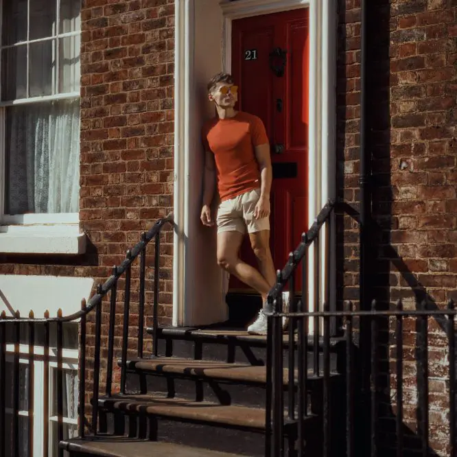 Influencer in an orange top standing in a Georgian doorway with black railings