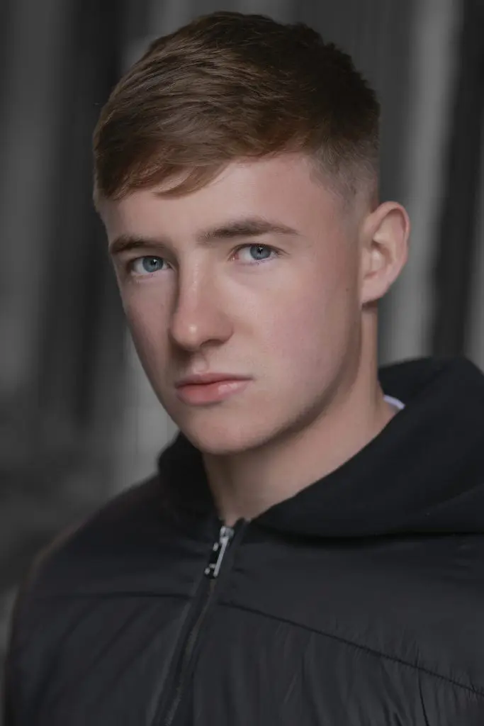 Natural light headshot of a young actor in a black jacket