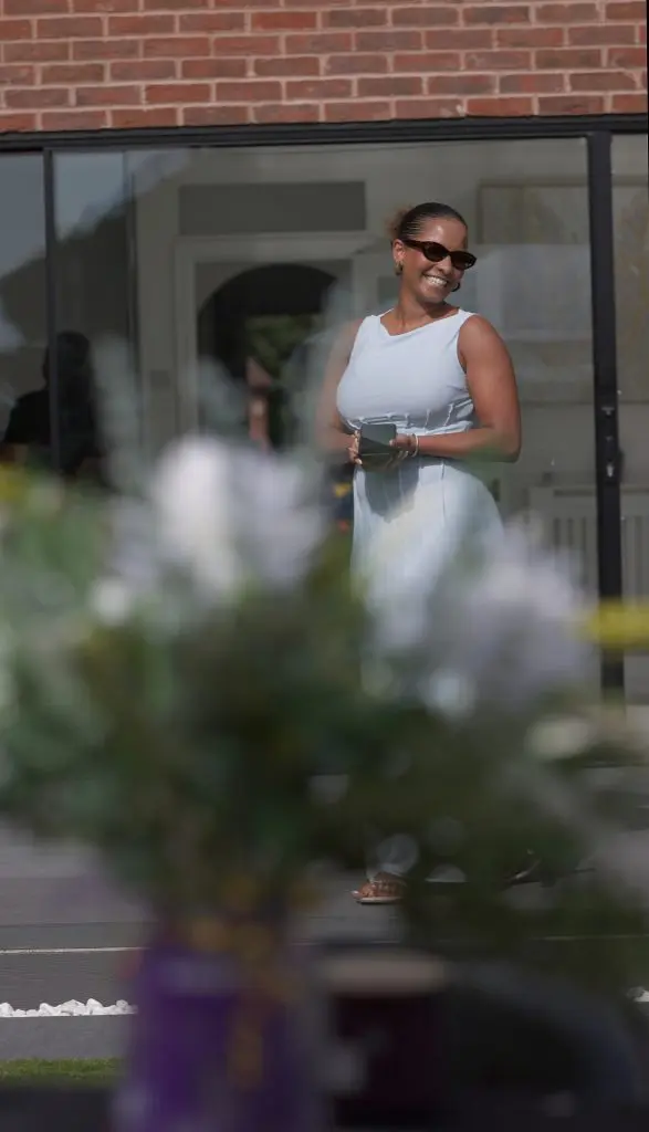 Woman in a white dress walking past a shopfront framed by flowers