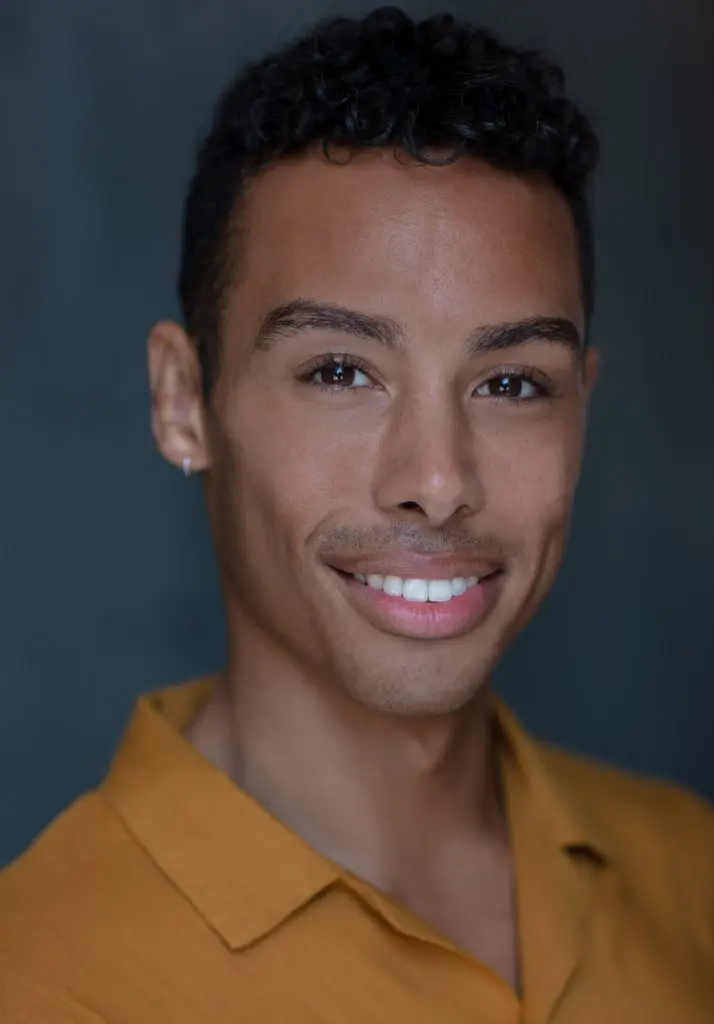 Smiling corporate headshot of a man in a mustard polo shirt