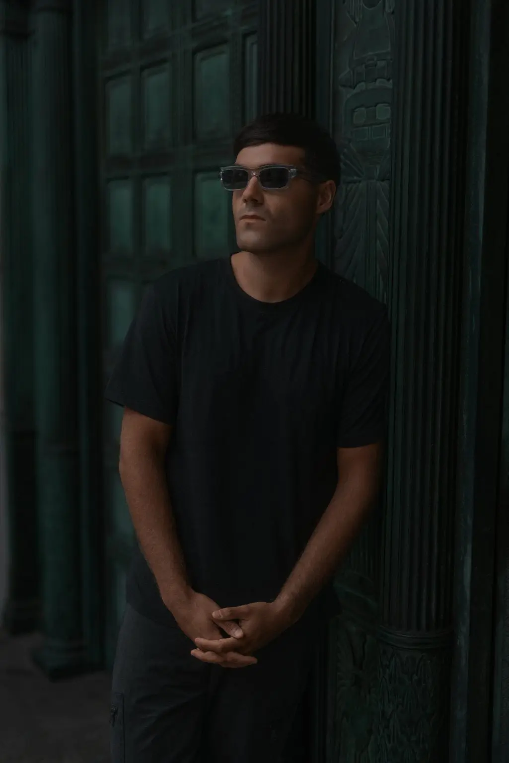 DJ Huzey in sunglasses standing in a grand green doorway on Water Street, Liverpool, for a press shot