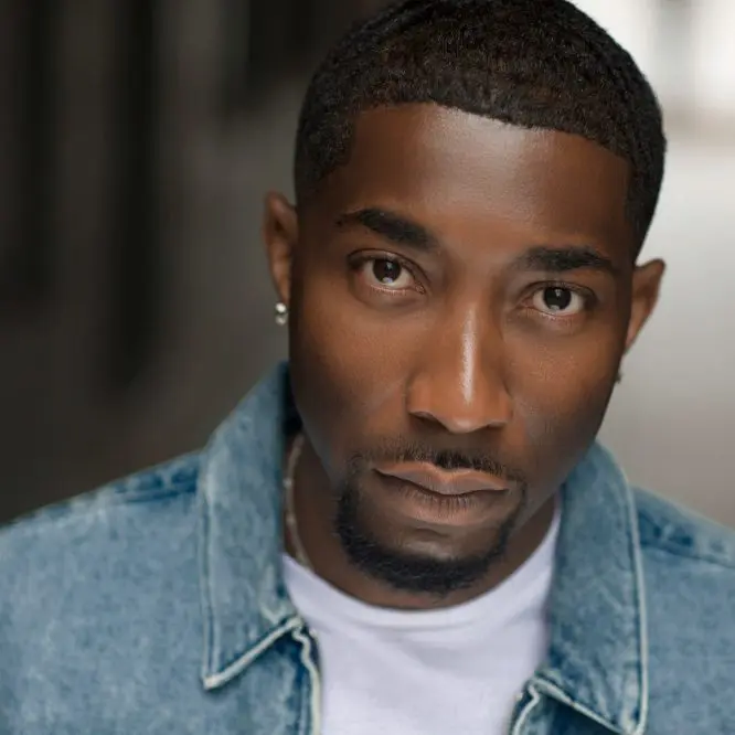 Recording artist in a denim jacket and white t-shirt looking into the camera