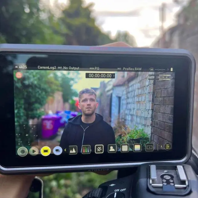 A staff interview being filmed on location, framed on the camera monitor