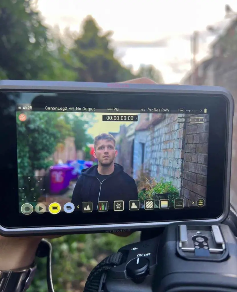 A staff interview being filmed on location, framed on the camera monitor