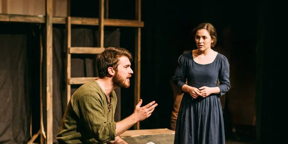 Two actors performing a scene on stage in period costume