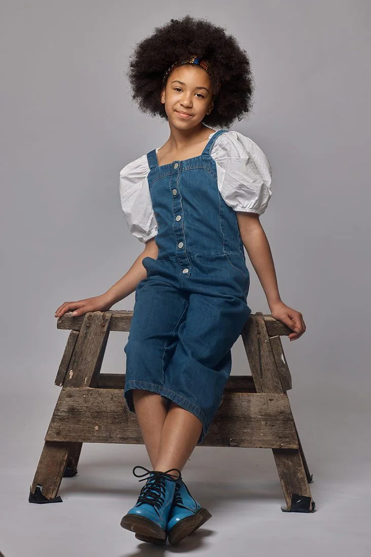 Model in denim dungarees and a white puff sleeve top photographed on model in a Liverpool studio