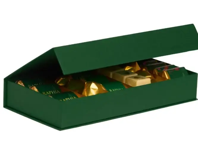 Open green gift box of gold-wrapped chocolates on a white background