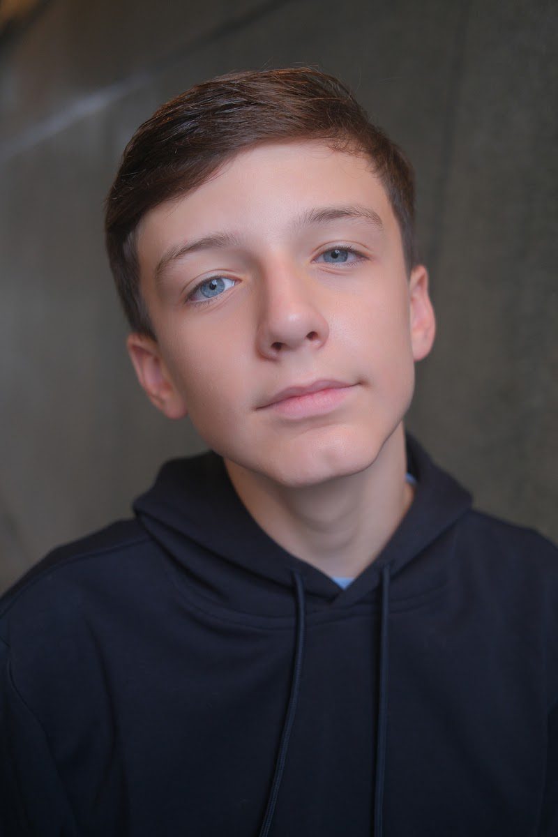 Young actor in a navy hoodie, head slightly tilted, serious expression in the studio