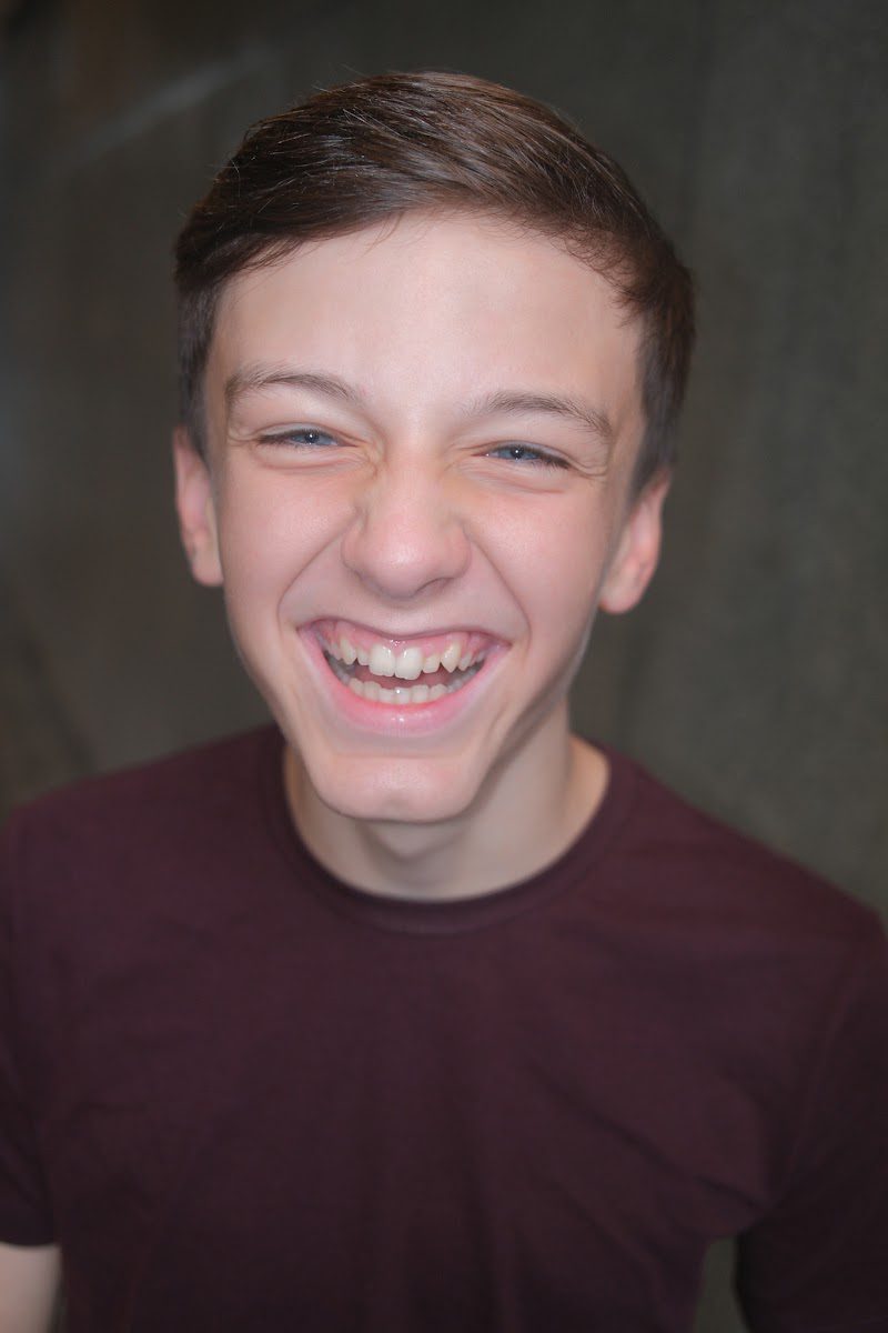 Young actor in a burgundy t-shirt mid laugh, natural commercial headshot