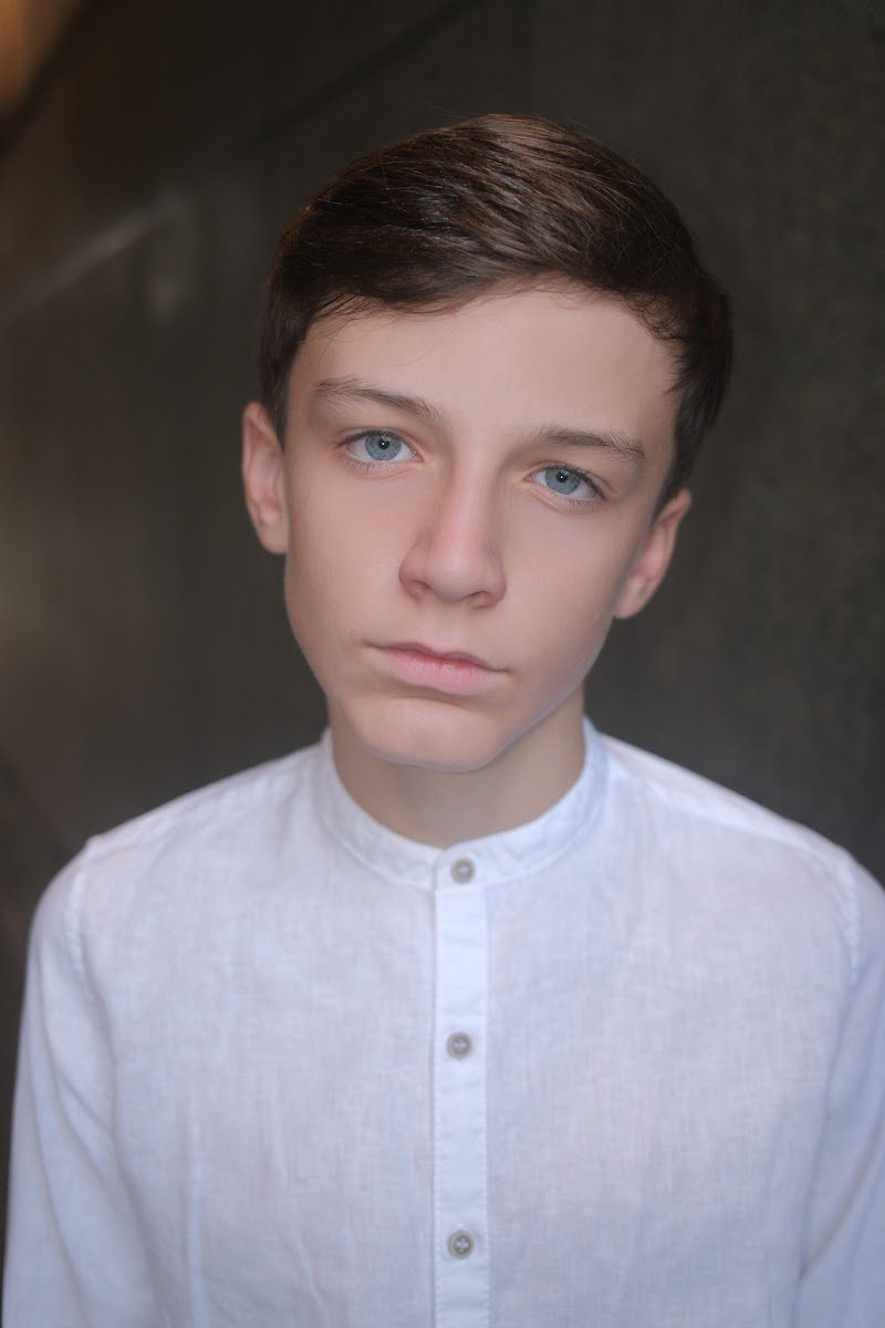 Young actor in a white collarless shirt with a calm, neutral expression