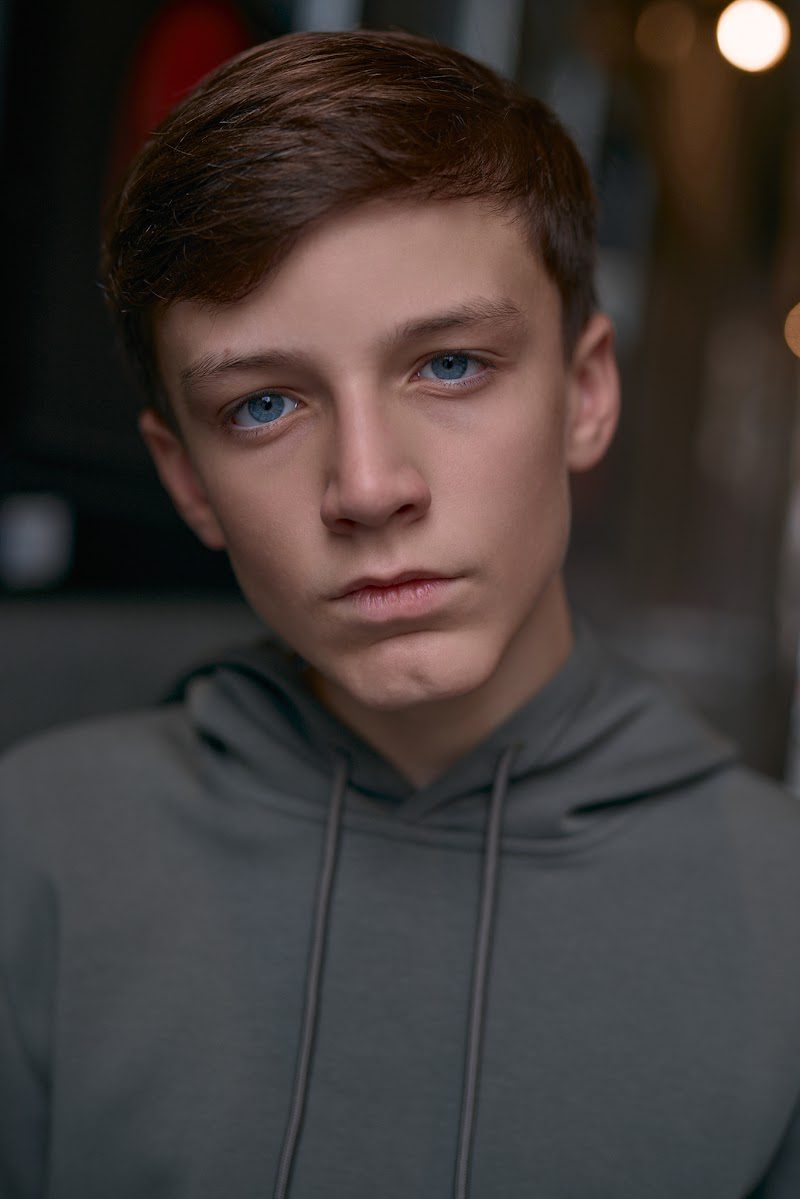 Young actor in a grey hoodie on location in Liverpool, still, thoughtful expression
