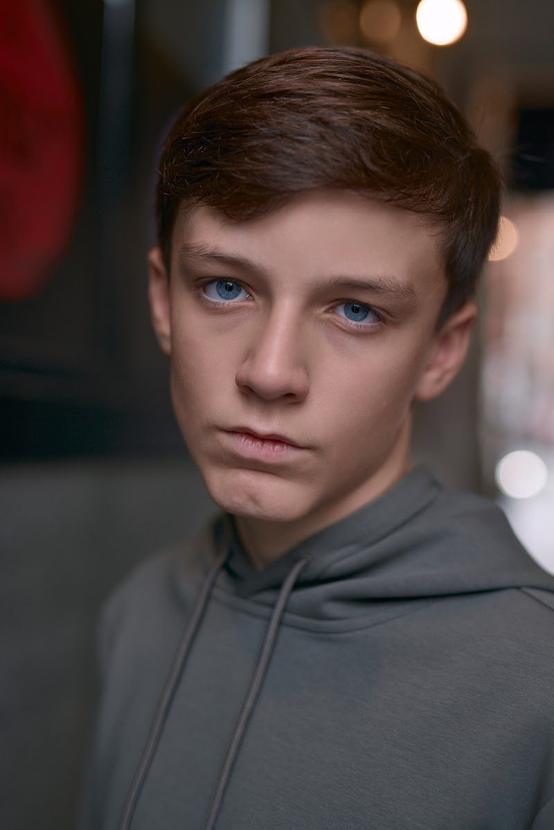 Young actor in a grey hoodie on location in Liverpool, serious look, head slightly lowered