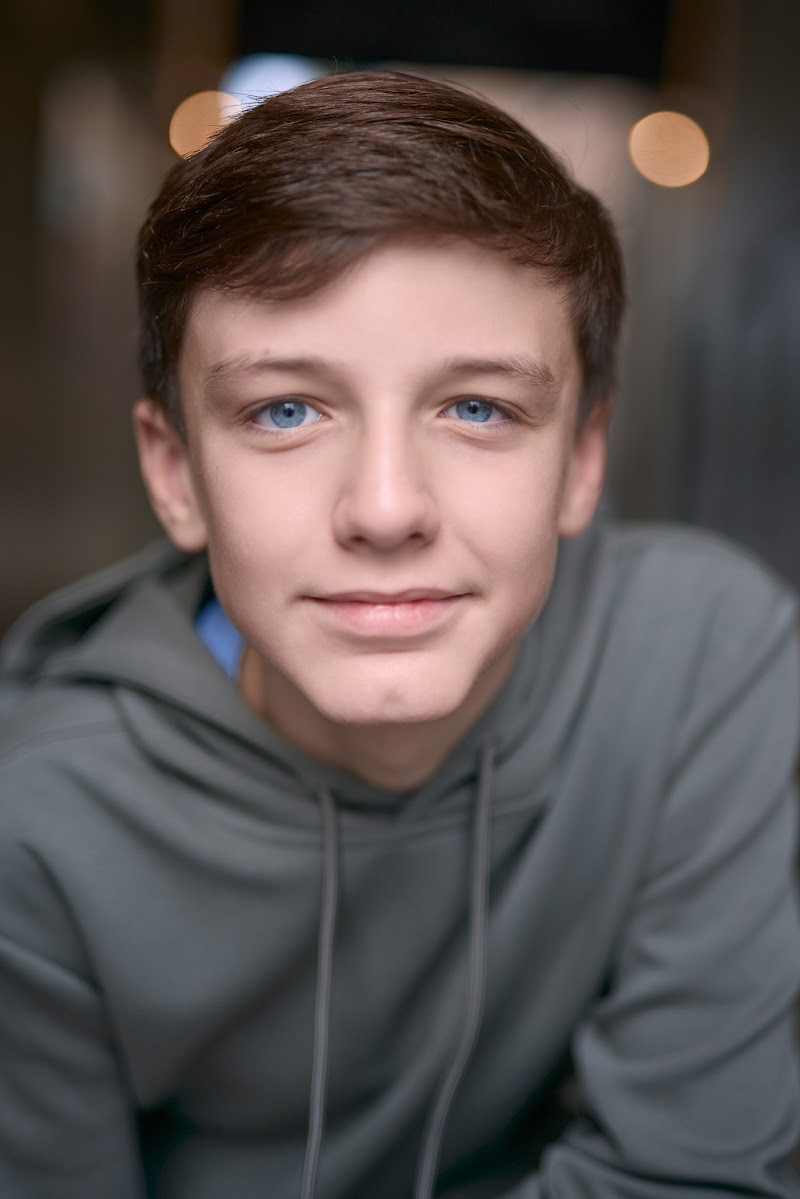 Young actor in a grey hoodie, open, friendly smile on location