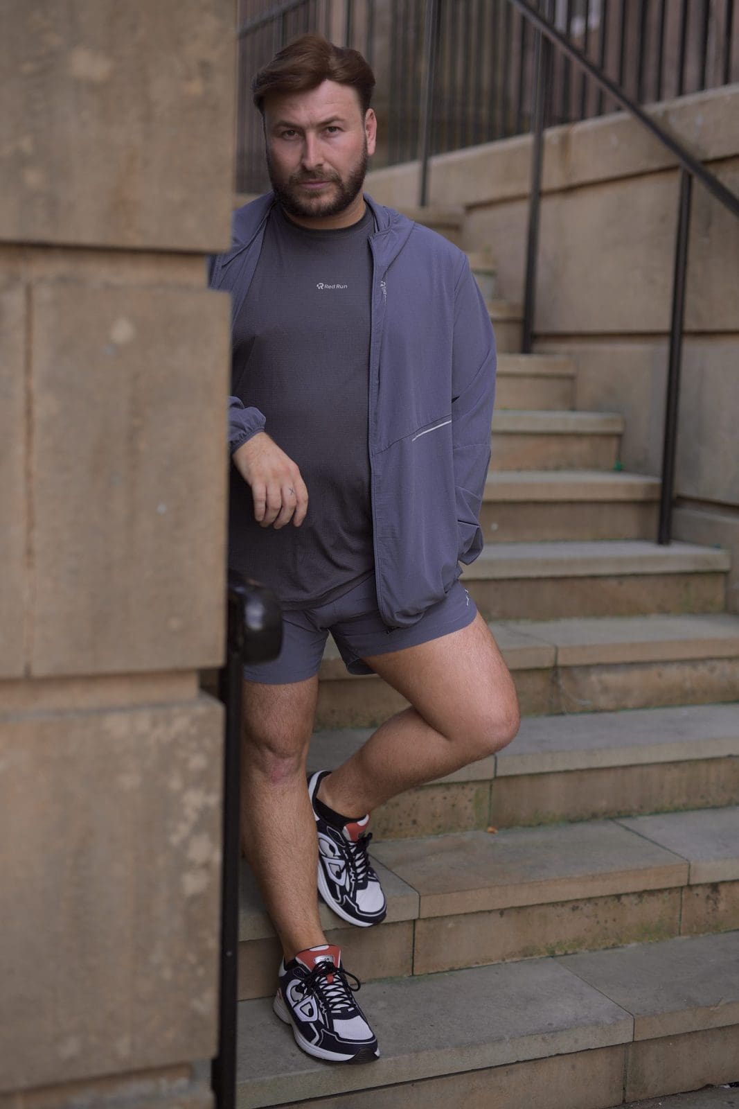 Man in a purple co-ord leaning on a handrail on stone steps, personal branding location shoot in Liverpool by Captured By Luke Media