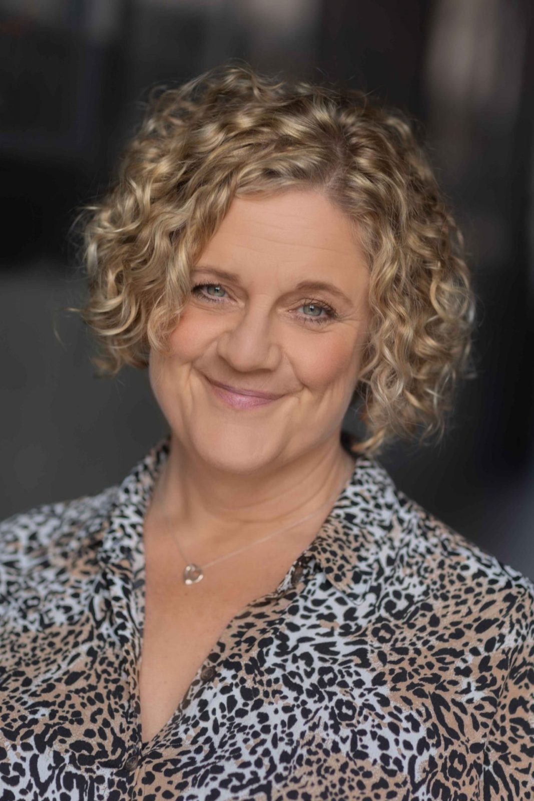 Smiling woman with curly hair in a patterned blouse, personal brand portrait in the Liverpool studio
