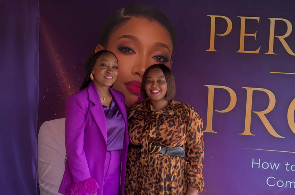 Author in a purple suit with a guest in front of her Permission to Prosper book launch backdrop in Liverpool, personal branding photography